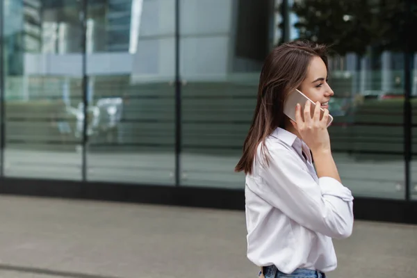 Meşgul kadın Yöneticisi dışında hücre telefon ile cep telefonu ile konuşurken ve şehrin sokak yürüyüş kadın arıyor. Uzaktan çalışma ve kablosuz bağlantı kavramı. Kopya alanı metin veya tasarım için