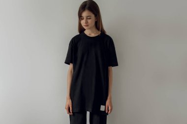 Logo veya tasarım için boş yer olan siyah bir boş tişört giyen hipster kız. Siyahlı kadın fotoğrafı pamuk t-shirt. Yatay mockup