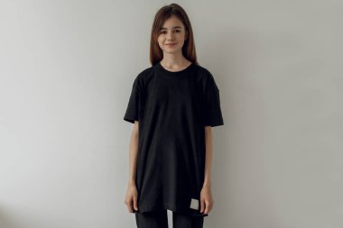 Mock-up boş siyah t-shirt, beyaz arka plan boş siyah tişört ve siyah kot giyen genç hipster gülümseyen kız