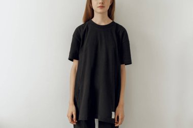 Boş siyah uzun t-shirt ve kot pantolon, mock-up için logo veya tasarım alanı ile siyah t-shirt giyen genç hippi kız resim kırpılmış, beyaz duvar arka planda