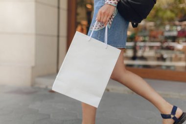 Beyaz Kağıt alışveriş çantası mockup. Çekici kız alışveriş merkezinde alışveriş yaparken. Logo veya tasarım için alan. Arka planda bulanık vitrin