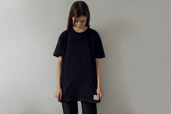 Logo veya tasarım mock-up şablon tişört, beyaz duvar içinde belgili tanımlık geçmiş Kopyala yeri olan boş siyah uzun t-shirt giyen genç ve güzel sportif kız,