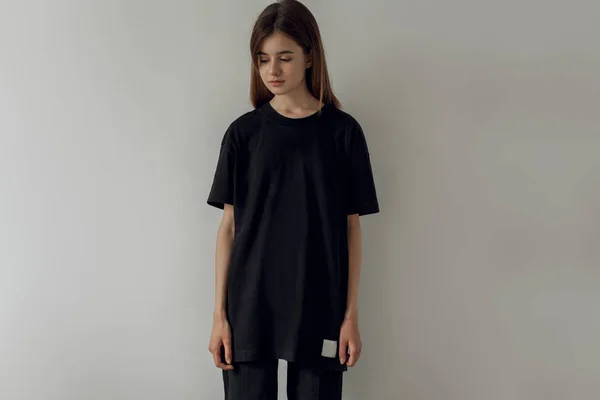 Logo veya tasarım için boş yer olan siyah bir boş tişört giyen hipster kız. Siyahlı kadın fotoğrafı pamuk t-shirt. Yatay mockup