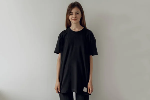 Mock-up boş siyah t-shirt, beyaz arka plan boş siyah tişört ve siyah kot giyen genç hipster gülümseyen kız