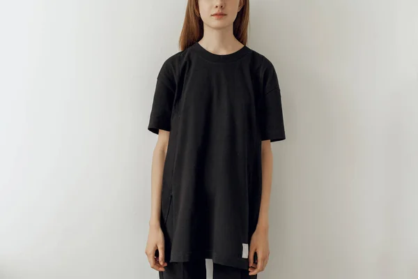 Boş siyah uzun t-shirt ve kot pantolon, mock-up için logo veya tasarım alanı ile siyah t-shirt giyen genç hippi kız resim kırpılmış, beyaz duvar arka planda