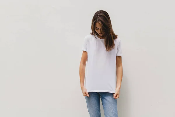 Genç güzel logo veya tasarım, model siyah pamuk t-shirt, beyaz duvar arka planda yeri olan boş beyaz t-shirt giyen kız. Önden görünüm