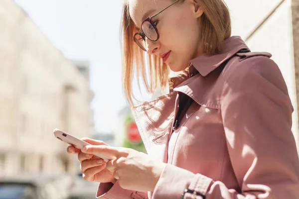 Başarılı kadın girişimci genç kadın cep telefonu dışında tarama cadde boyunca yürüyüş cep telefonu kablosuz bağlantı kullanarak, modern smartphone aygıtı kullanarak mutlu gülümseyen iş kadını