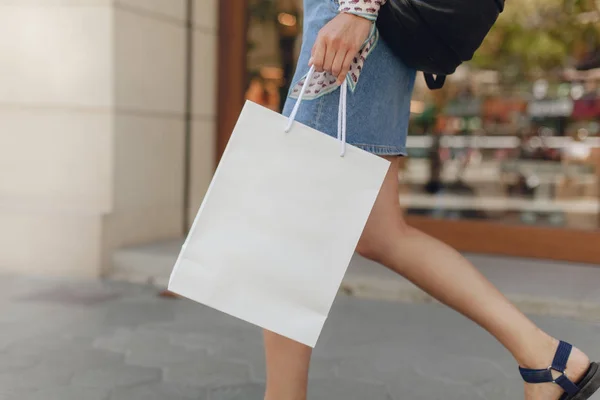 Beyaz Kağıt alışveriş çantası mockup. Çekici kız alışveriş merkezinde alışveriş yaparken. Logo veya tasarım için alan. Arka planda bulanık vitrin