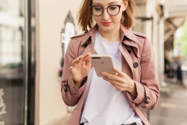 Başarılı kadın girişimci genç kadın cep telefonu dışında tarama cadde boyunca yürüyüş cep telefonu kablosuz bağlantı kullanarak, modern smartphone aygıtı kullanarak mutlu gülümseyen iş kadını