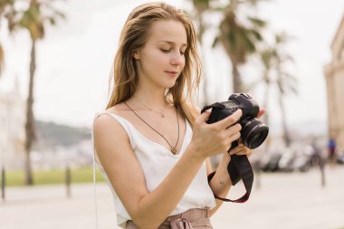 Çok gülümseyen kız dslr kamera resim çekme ve ekran ayarları kontrol. Profesyonel kadın fotoğrafçı yolcu parkta fotoğraf makinesinde çekim. Yaz, yeşil park açık havada