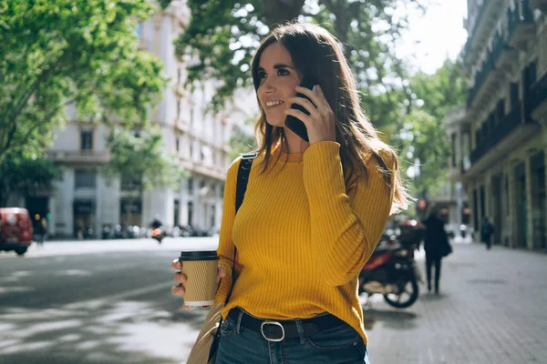 Güneşli bir yaz gününde şehirde yürüyen mutlu bir kadının hayat tarzı portresi. Sıradan giyinmiş güzel bir kız. Akıllı telefon cihazıyla konuşuyor.