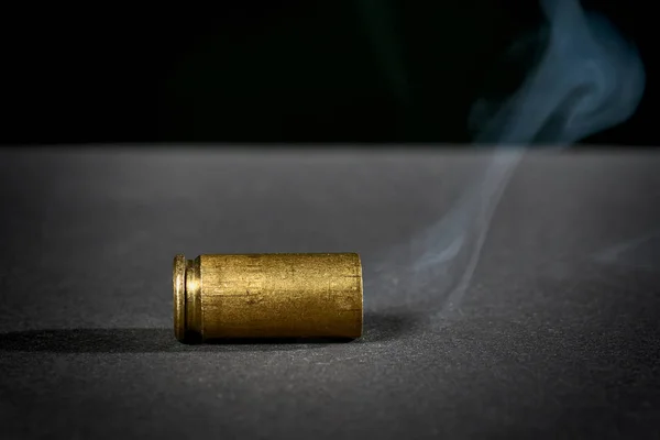 吸烟的弹壳刚刚从扔在地上的手枪中射出 — 图库照片