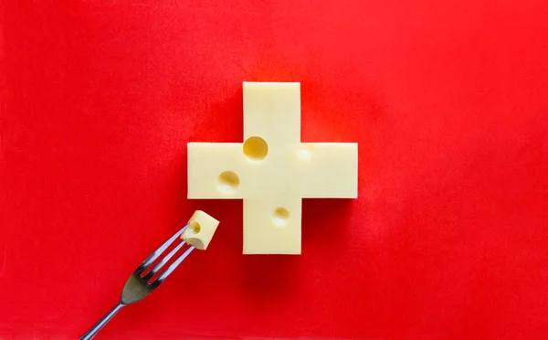 Cruz Suiza Forma Queso Sobre Fondo Rojo Con Una Pieza — Foto de Stock