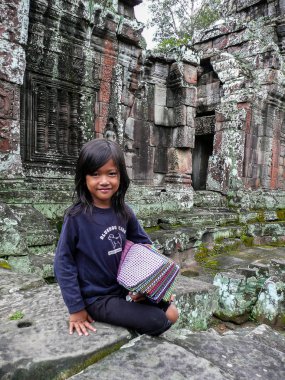 Angkor Wat, Kamboçya - 24 Ekim. 2008: gülümseyen genç kız satmaktadır kumaşlar souviner Anglor Wat turistler için tapınak kalıntıları.