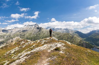 Alpler 'in dağlık zirvesinde, Grimsel Vadisi 'ne bakan Hiker ayakta, Isviçre