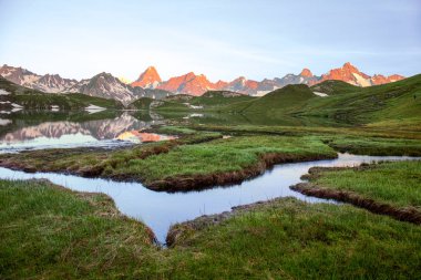 Güneşin doğuşunda ve Grand Jorass 'da yansıması olan Lacs de Fenetre' de kurak dereleri olan bataklıklar Val Ferret; Mont Blanc; dağ arka planında Col de Grand Saint Bernard, İsviçre