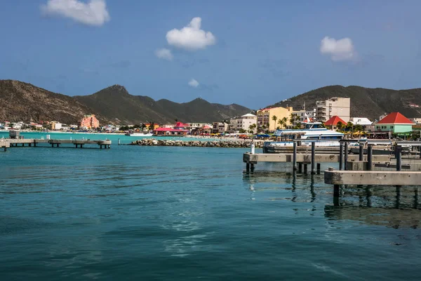 A scenic look at a marina with beach, hotels and mountains off in the distance.