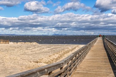 A long fishing pier with beach sand being replaced in Bayshore Waterfront Park in Monmouth County NJ. clipart