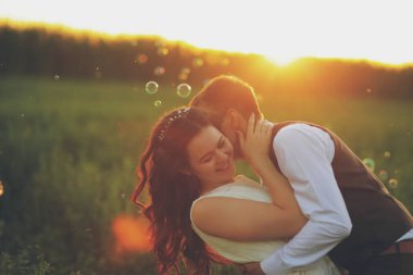 Mutlu gelin ve damat gün batımında parkta birbirlerine sarılırlar. Sabun köpükleri. Düğün için. Mutlu aşk konsepti. Yüksek kalite fotoğraf