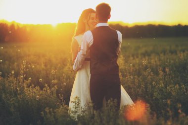 Mutlu gelin ve damat gün batımında parkta birbirlerine sarılırlar. Düğün için. Mutlu aşk konsepti. Yüksek kalite fotoğraf