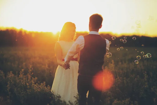 Νύφη Και Γαμπρός Κρατούν Χέρια Χορεύοντας Στο Πάρκο Ηλιοβασίλεμα Φυσαλίδες — Φωτογραφία Αρχείου