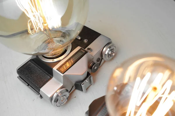 グレーの背景にエジソンランプ付きの古いカメラからのレトロなランプ コンセプトは良いアイデアです 高品質の写真 — ストック写真