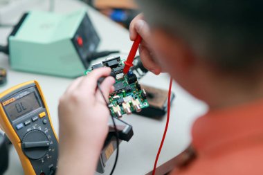 Bir adamın elleri aletlerin onarımıyla, elektronik hizmetlerin imalatıyla lehimleme devre kartının elle montajıyla meşguldür. Yüksek kalite fotoğraf