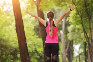 Genç kadın, doğa ormanında sporla meşgul. Sağlıklı bir yaşam sürüyor. Motivasyon, yaşama uygun. Koşu ayakkabısı. Güzel güneş ışığı. Koşmadan önce kadın ısınıyor