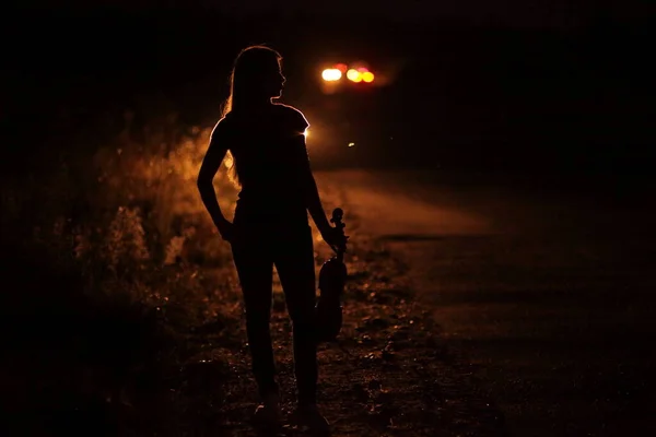 Arabanın Farlarında Keman Işığı Olan Ince Bir Genç Kadının Silüeti — Stok fotoğraf