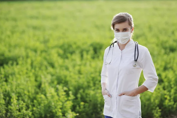 Vrouwelijke Arts Verpleegkundige Met Een Beschermend Gezichtsmasker Groene Grasondergrond Veiligheidsmaatregelen — Stockfoto