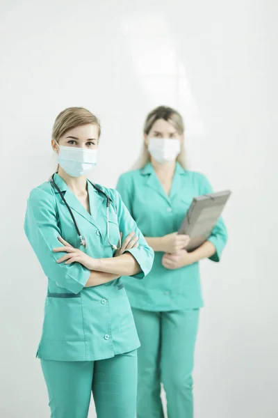 Twee vrouwelijke artsen met medische maskers die naar de camera kijken. Stethoscoop op de hals — Stockfoto