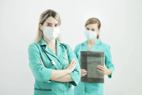 两名戴口罩的女医生看着摄像机。颈上的听诊器 — 图库照片