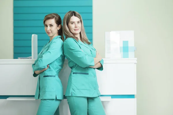 Két női orvos vagy nővér nézi a kamerát. A kórház recepcióján. — Stock Fotó