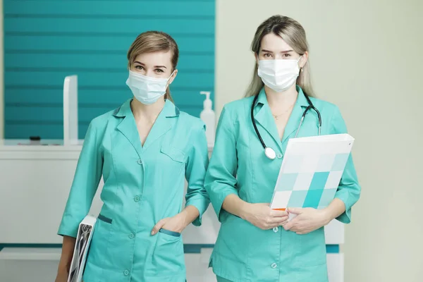 Zwei Ärztinnen in medizinischen Masken blicken in die Kamera. Stethoskop am Hals — Stockfoto
