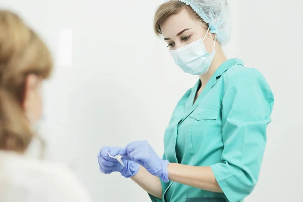 Uma enfermeira usando uma máscara médica abre um lenço de álcool descartável. — Fotografia de Stock