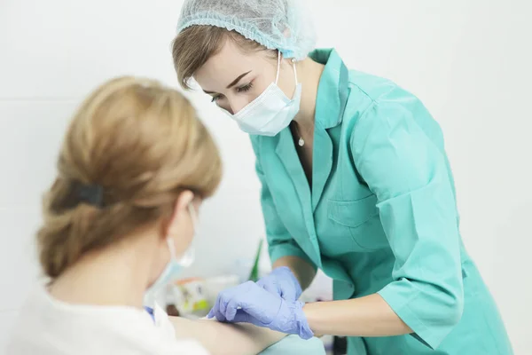 Uma enfermeira em uma máscara médica faz um exame de sangue de um paciente. — Fotografia de Stock