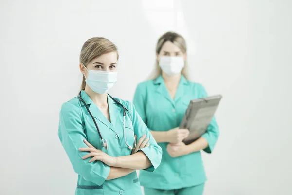 2人の女性医師または看護師がカメラを見て医療マスクを着用している 首の聴診器のフォノ内視鏡 ストック画像