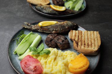 Tabakta kızarmış balık, biftek ve sebze. Beton gri tezgah. Yüksek kalite fotoğraf