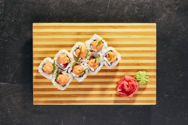 Japon Suşi roll ahşap tabak üzerinde baharatlı somon dilimi ile tepesinde