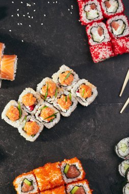 Asya menü. Rolls - Philadelphia, Alaska, California, yin-yang siyah arka plan üzerine kümesi. Üstten görünüm