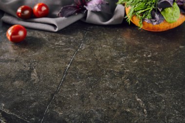 Karanlık taş yeşil bir grup ile arka plan ve mor fesleğen ahşap kase. Gri peçete, domates ve dağınık tuz tarifi şablon seçici odak için doğal bulanık çerçeve