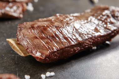 Sıcak ızgara bütün Külbastı siyah taş zemin üzerine. Taze sulu Orta nadir sığır eti Grillsteak. Barbekü et yakın çekim