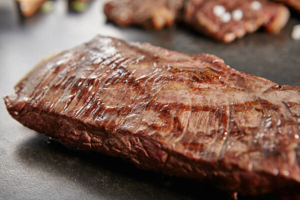 Hot Grilled Whole Flank Steak on Black Stone Background. Fresh Juicy Medium Rare Beef Grillsteak. Barbecue Meat Close Up