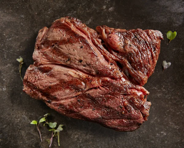 Hot Grilled Whole Alternative Steak on Black Stone Background. Fresh Juicy Medium Rare Beef Grillsteak. Barbecue Meat Top View Close Up