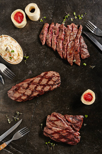 Hot Juicy Whole Machete Steak and Denver Steak on Barbecue Grill Background. Fresh Medium Rare Beef Grillsteak and Well Done Bbq Entrecotes. Thick Slices of Fried Meat from an Alternative Cut Top View