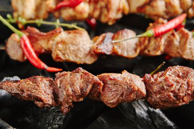 Izgara kuzu kebabı veya Barbekü şaşlık otlar ve baharatlar Closup kömür zemin üzerine sıcak. Makro fotoğraf saptırılmış ızgara küpleri koyun eti, kırmızı biber ve kekik ile baharatlı dekore