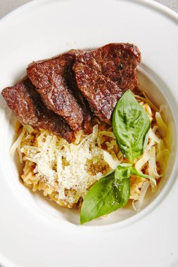 Izgara beyaz tabak üstten görünüm içinde sığır eti dilim mantar Risotto. Geleneksel İtalyan kremsi Arborio pirinç Aferin Dana ile ve Yeşil fesleğen