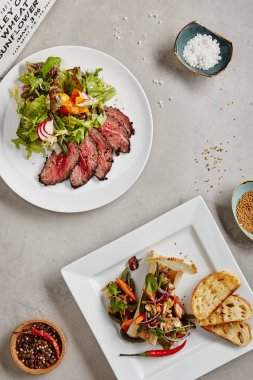 Izgara biftek salata veya yeşil karışımı ile Pazar rostosu. Kavrulmuş baharatlı kemik iliği tost ve sebze üstten görünüm ile kapatın. Sıcak Barbekü Orta nadir mermer et beyaz plaka üzerinde ince dilimler