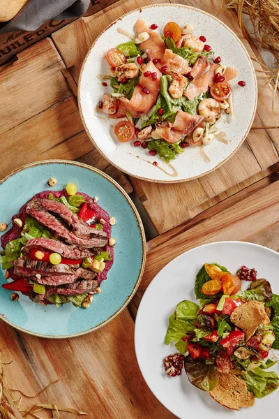 Somon salata karides, marul, badem, nar, kiraz domates ve sos ile. Yeşiller ve fındık üstten görünüm ile Orta nadir Sığır biftek dilimlenmiş. Croutons ızgara sebze salatası