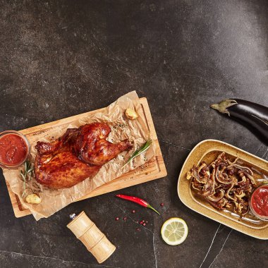 Yarısı Gürcü Adjika, baharatlar, bitkiler üzerinde rustik ahşap arka plan üstten görünüm ile tüm sıcak füme tavuk. İştah açıcı Barbekü tavuk soslu baharatlı domates, karabiber, biberiye ile dekore edilmiştir.